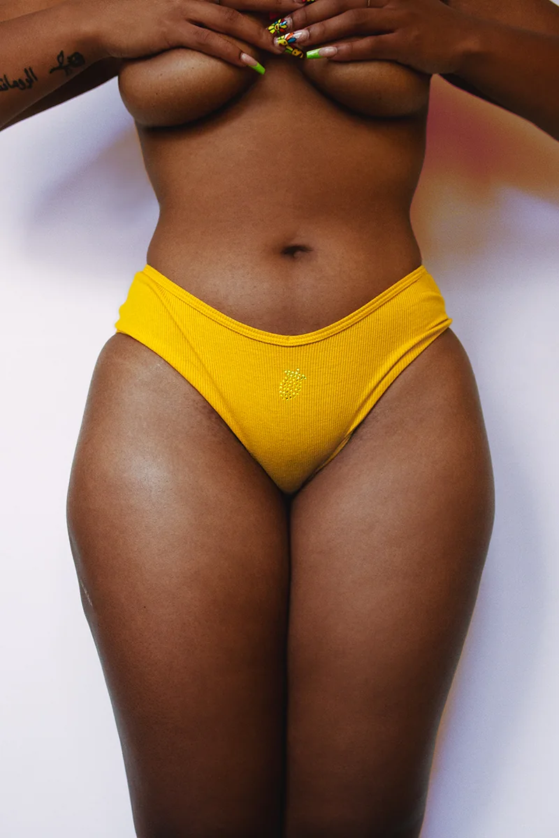 Artistic portrait of a Black woman holding her chest, natural beauty with curves, thick thighs, and visible cellulite, celebrating body confidence.