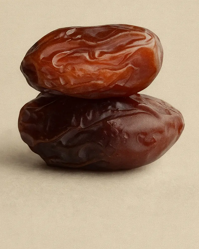 Two glossy Medjool dates stacked, symbolizing natural nourishment and simplicity.