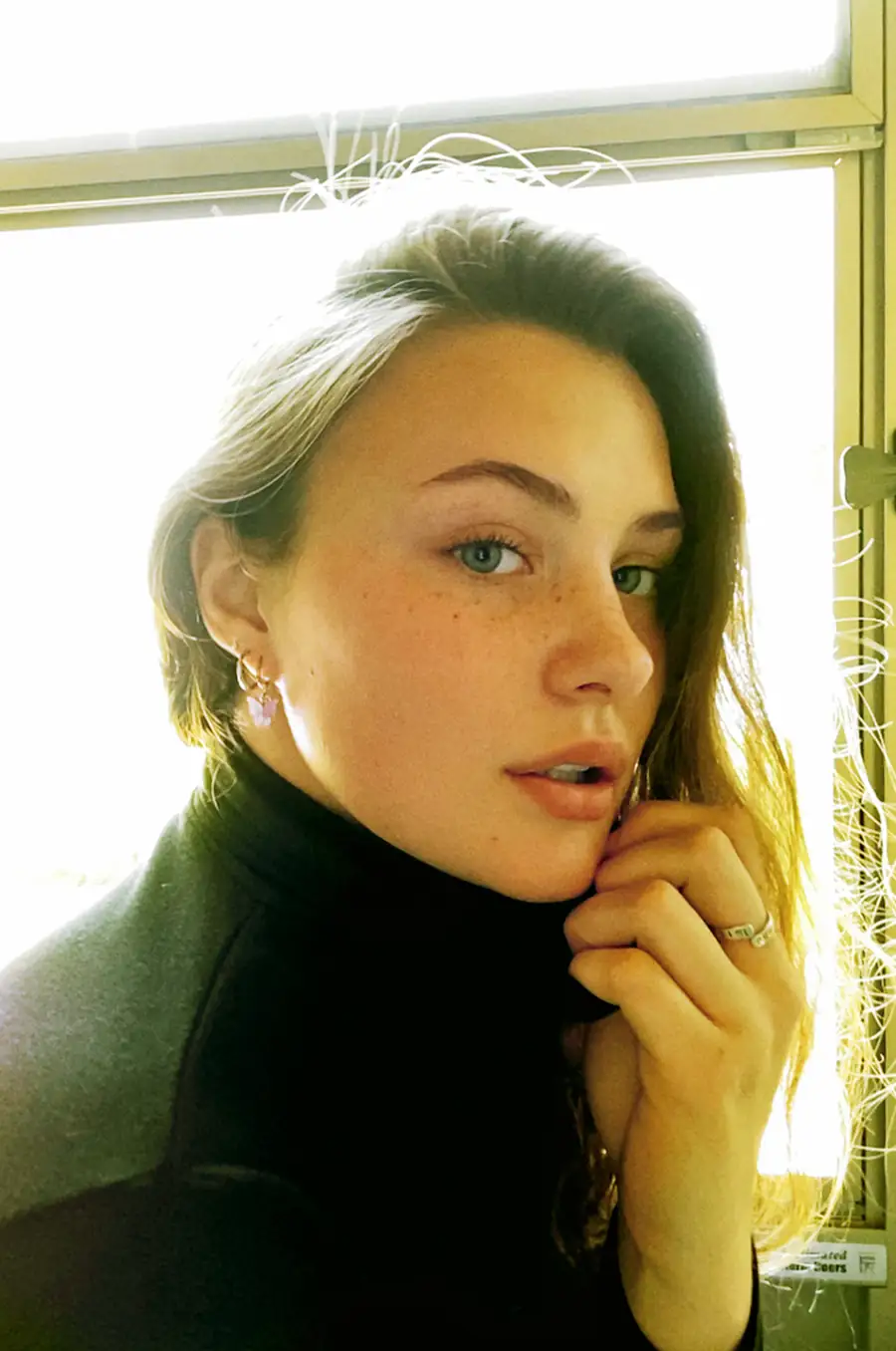 Close-up of Bare Model Gibson during a FaceTime shoot, natural skin texture, freckles, and soft light emphasizing authenticity.