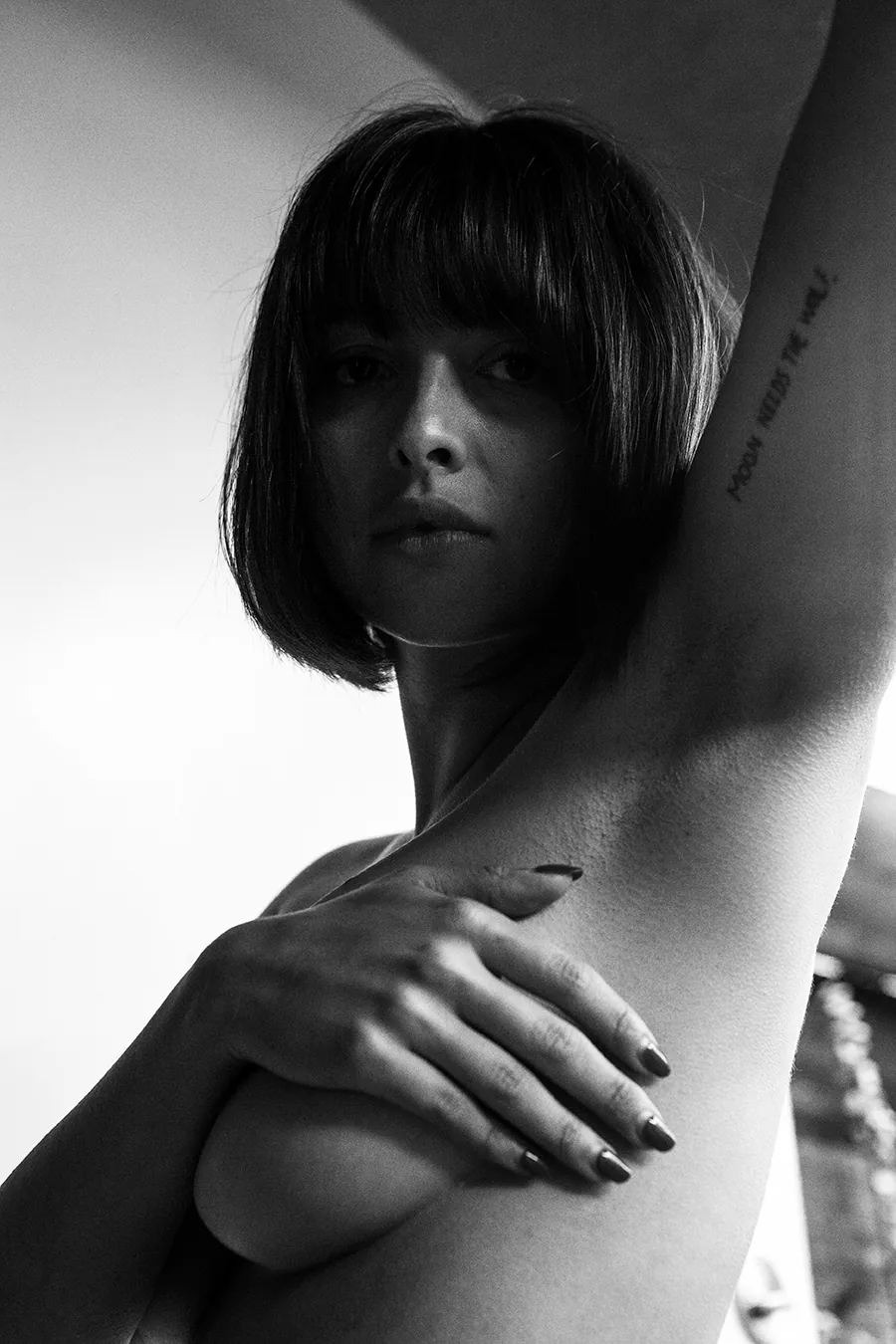 Black and white portrait of Irene Noren with arm raised, captured in soft light, focusing on texture, form, and stillness
