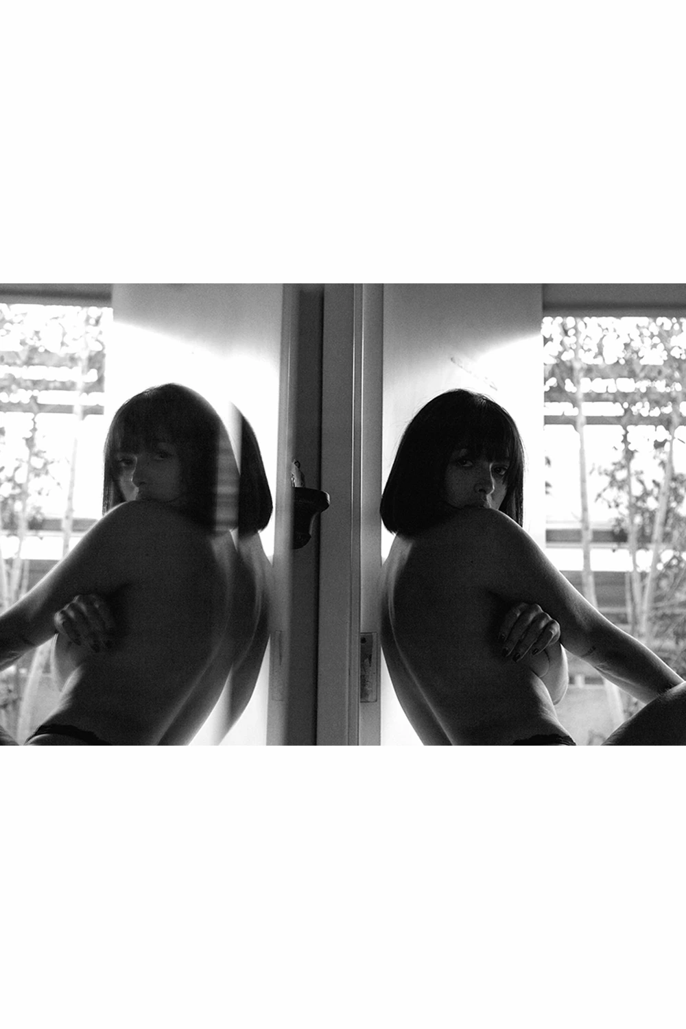 Black and white mirrored portrait of Irene Noren framed in a doorway, exploring reflection, symmetry, and quiet presence in an editorial photo essay