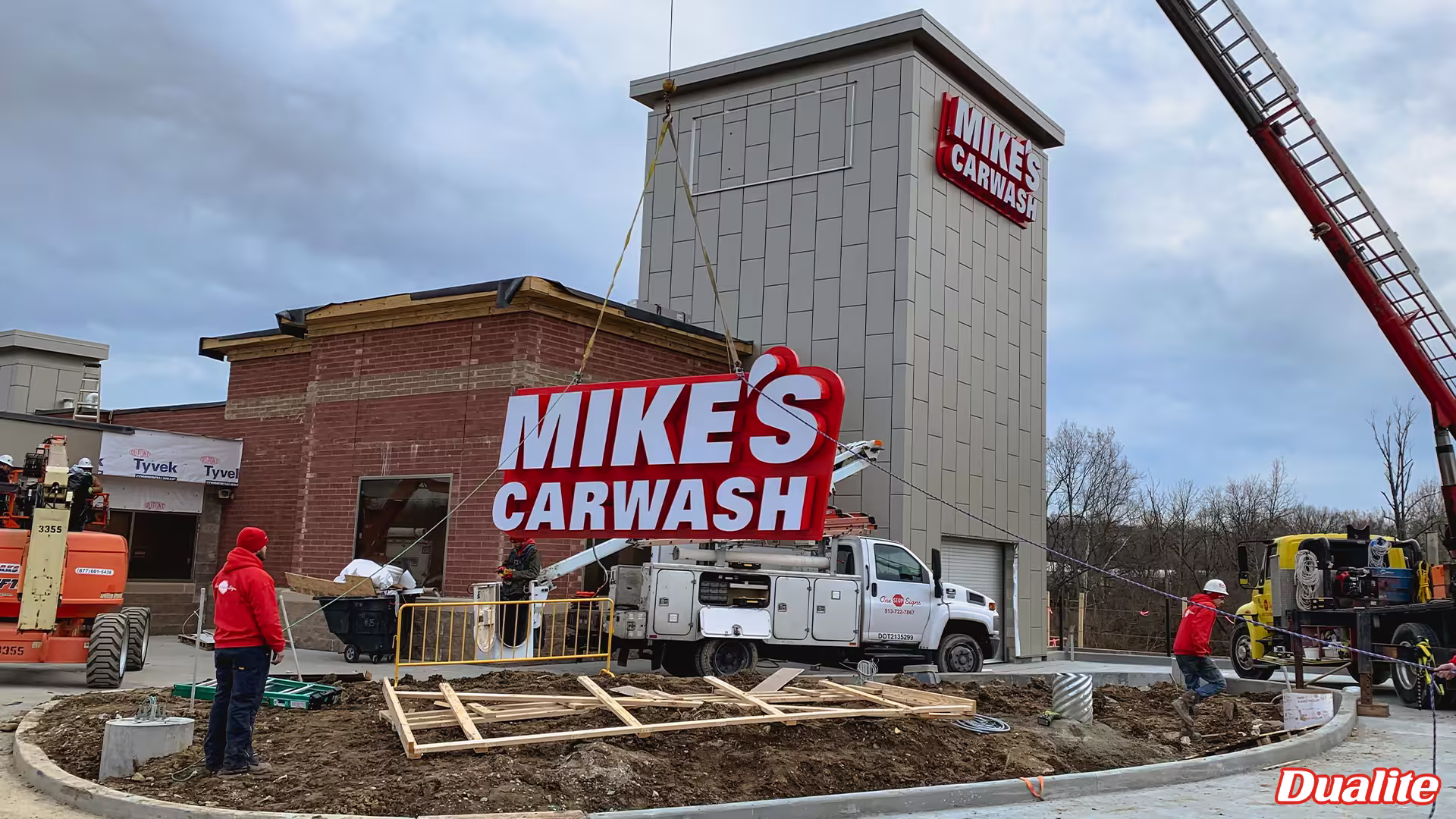 Dualite installation crew placing large Mike’s Carwash signage on a new car wash location during site construction.