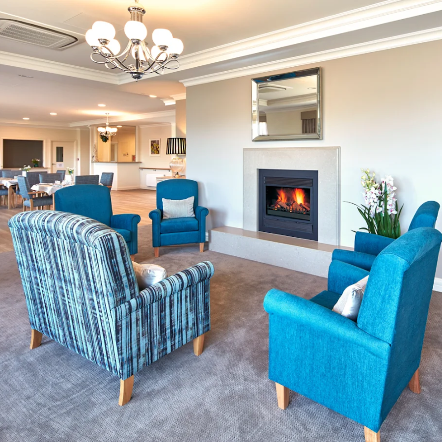 A warm lounge with comfortable seating and a fireplace within aged care in Black Rock.