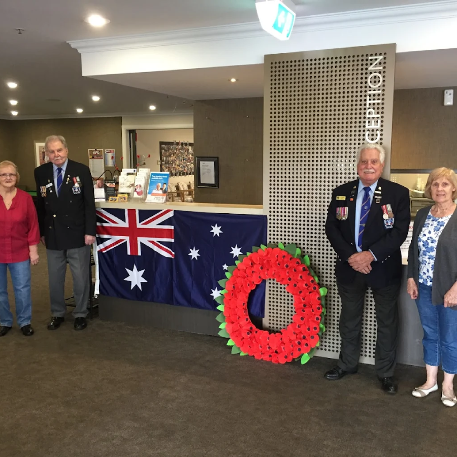 Residents at a nursing home in Endeavour Hills, VIC honouring Anzac Day with a wreath ceremony and Australian flag display.