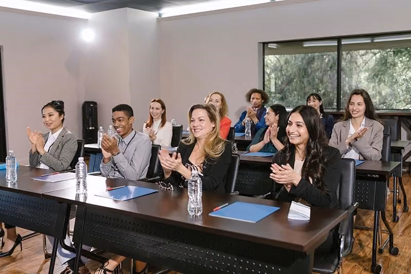 A group of employees clap for a colleague who received public recognition.