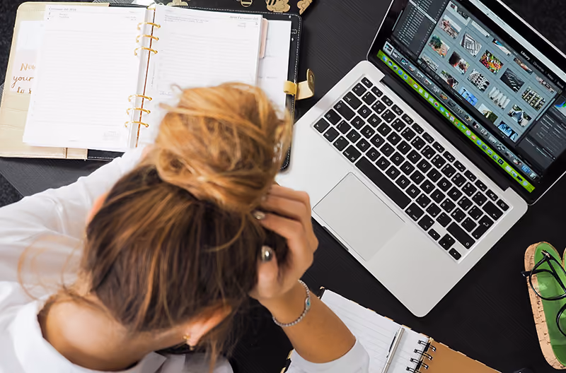 A frustrated employee holding her head while working.