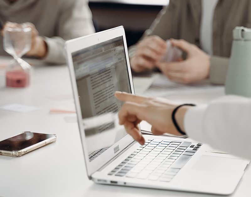 An HR professional pointing at a description of applciant tracking system features on a laptop screen. 