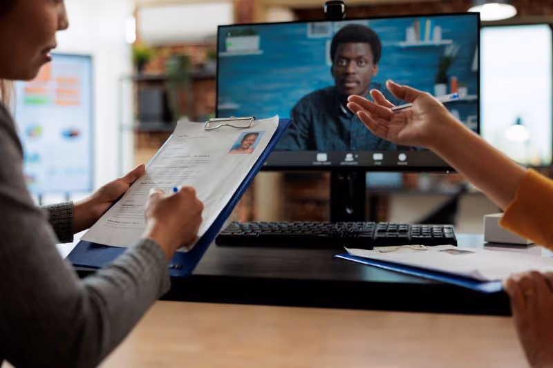 A recruiter and hiring manager interviewing a remote candidate with video interview software.