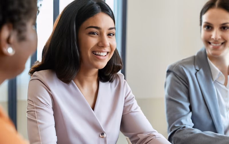 A candidate smiling during their job interview with recruitment professionals practicing active listening.