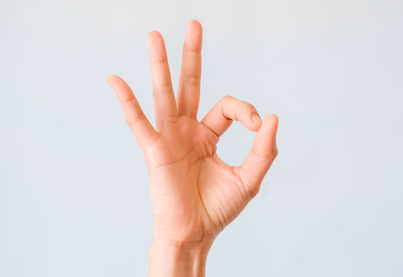 A hand with palm facing the camera performing the ‘OK gesture’ in response to positive feedback.