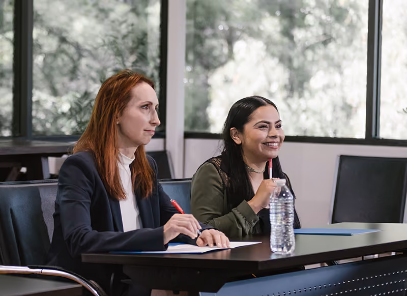 Two women in a conference room receive training as part of a company's returnship program.