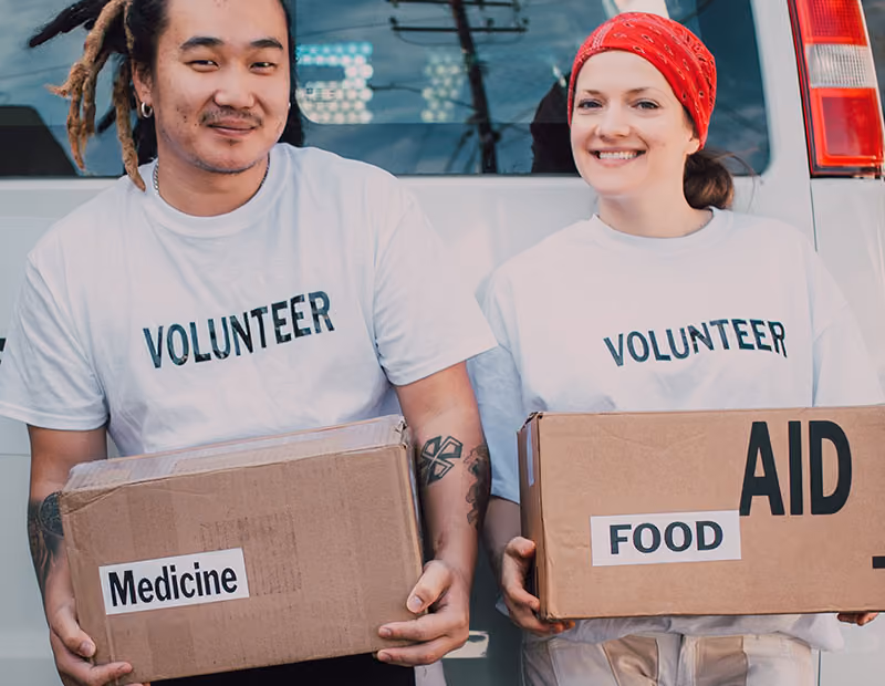 Two volunteers holding boxes of donated medicine and food.