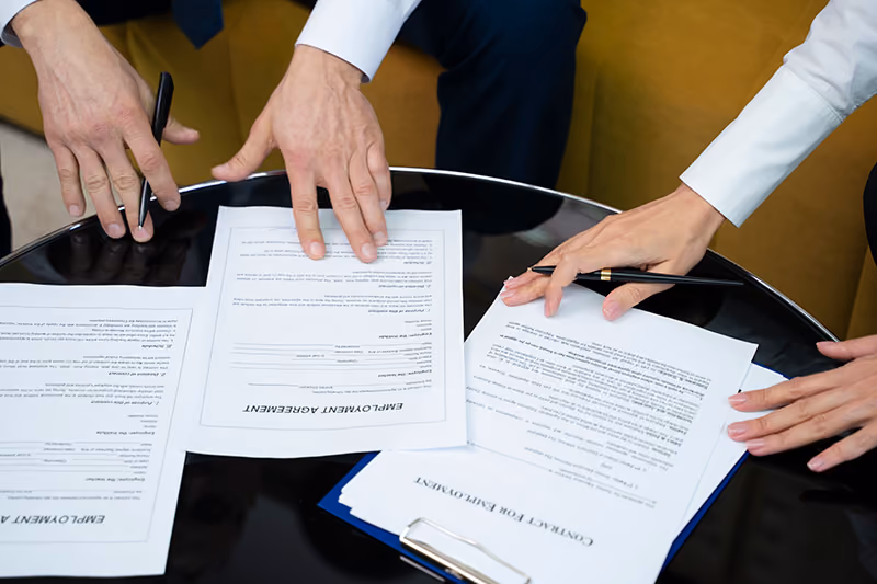 A human resources professional reviewing an employment contract to confirm the terms of resignation and the requirements of an employee offboarding process.