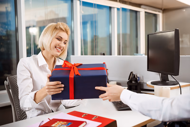 A delighted worker at her desk receiving a gift as an employee reward.