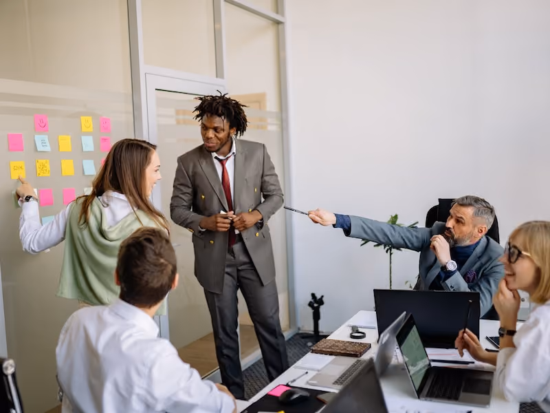 Employees in a meeting room discussing ideas for criteria of success to include in the organization's employee reward system.