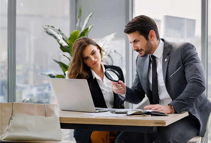 A micromanaging boss scrutinizing an employee's work with a magnifying glass.