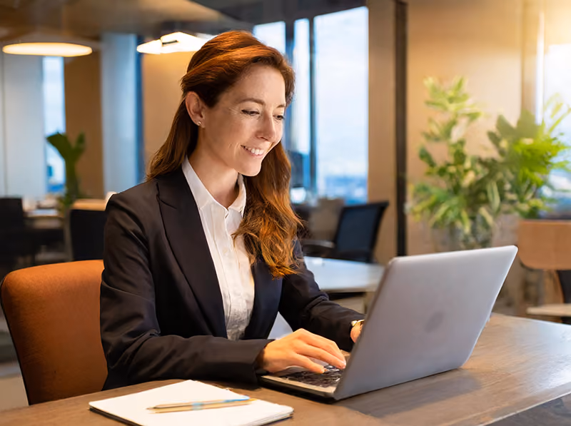 An HR professional using a laptop to write a workplace AI policy in an office environment.