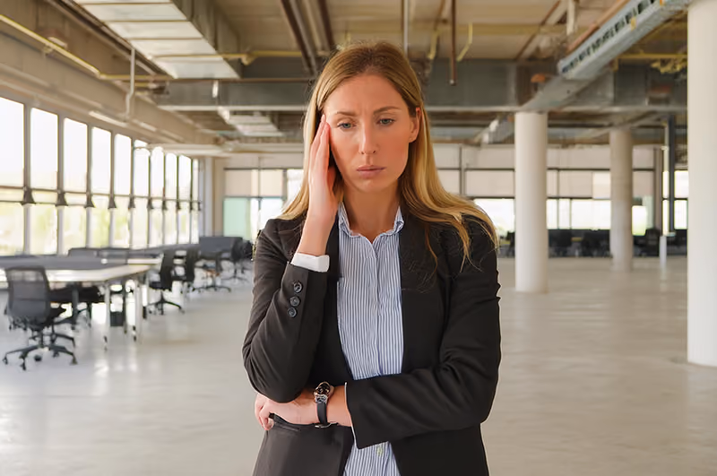 A manager standing in an empty office, concerned about the cost implications of a four-day workweek.