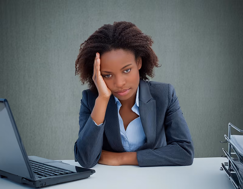 An employee distressed by workplace conflict sitting disengaged at her desk.