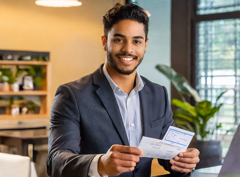 An employee holding the paycheck they received from an outsourced payroll provider.