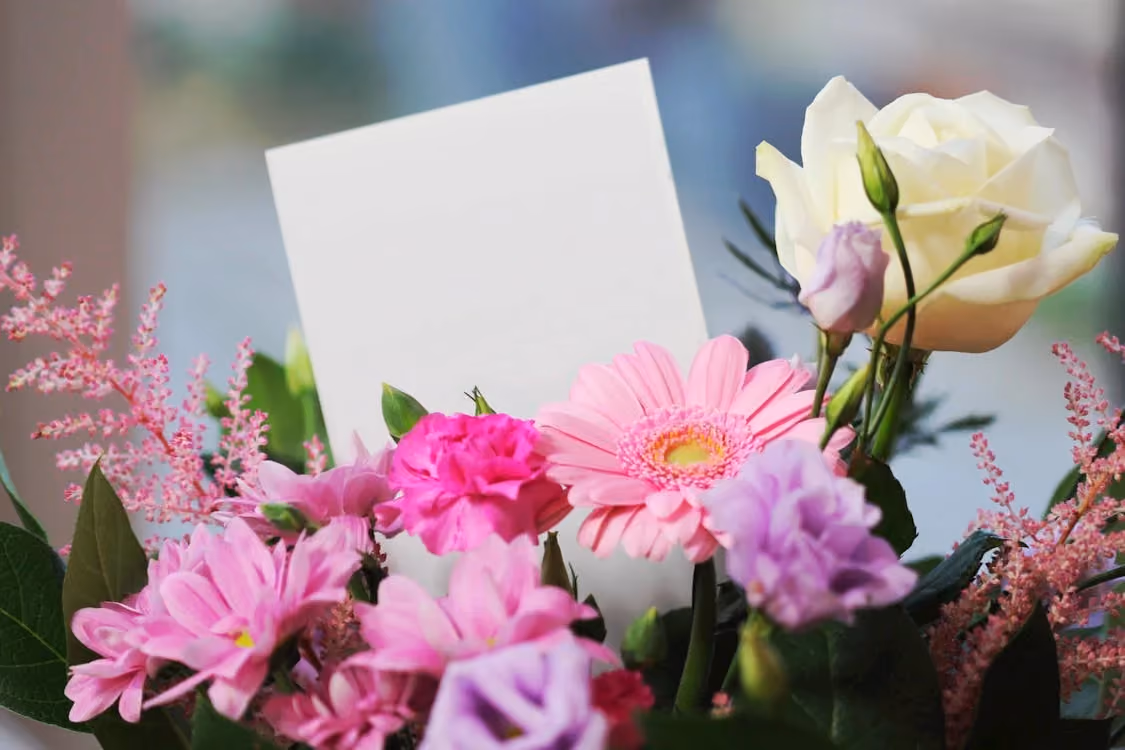 White rose and pink daisy bouquet with a thank you card