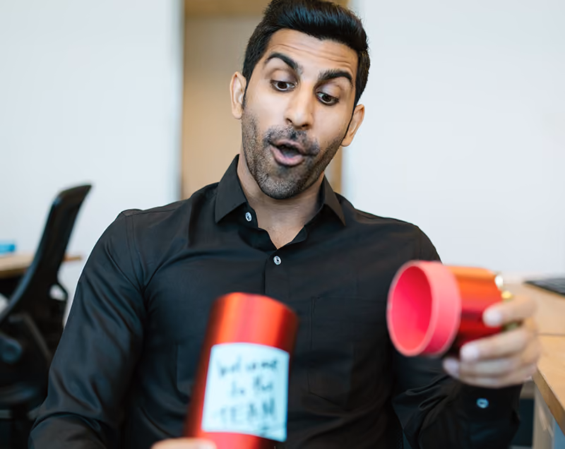 A new hire opening a funny welcome gift from the team at their new job.