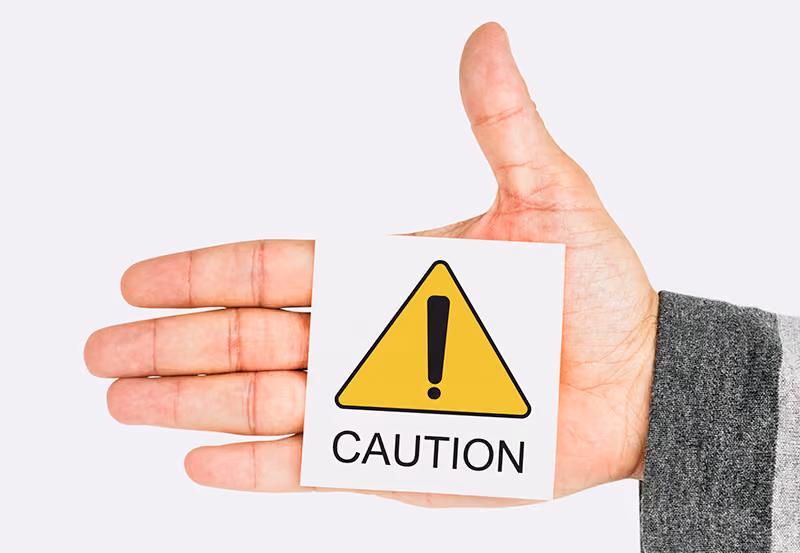 A hand holding a caution sign.