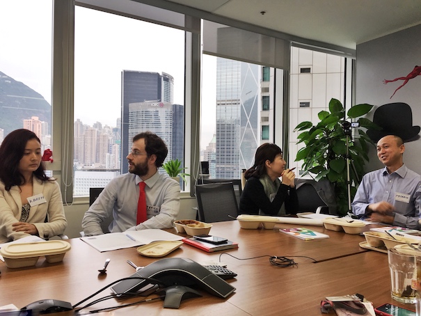 香港办公室内几位专业人士围桌开会，窗外可见城市景色的真实照片