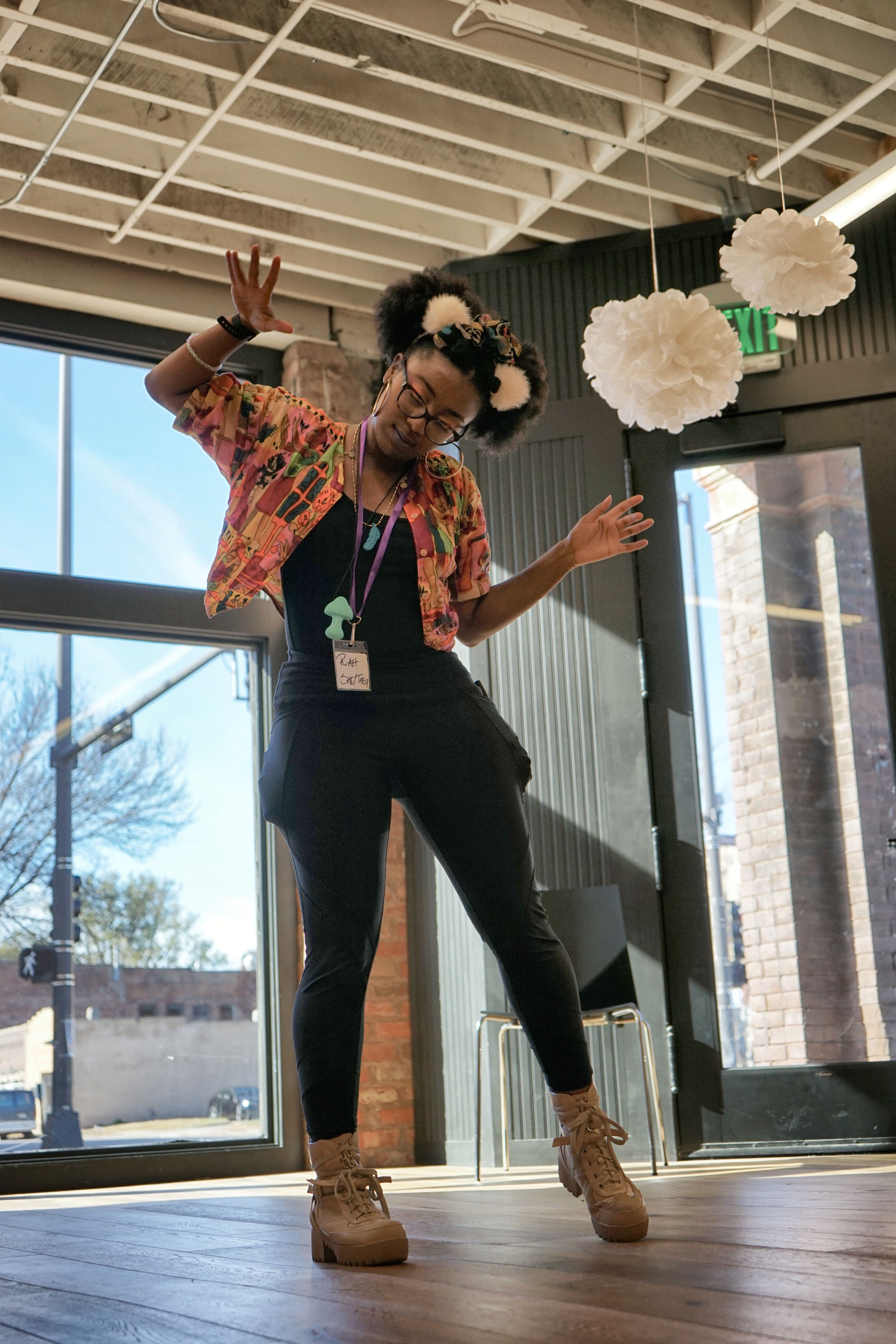 Riah stands in a well-lit room performing an artistic stimming dance.