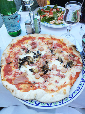 Image of a pizza loaded with meat and veggies in Florence, Italy