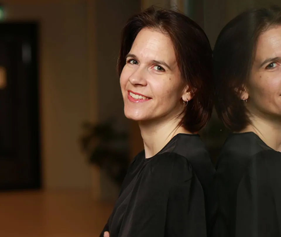 Woman in a black blouse leaning by reflective glass, warm light portrait at Workpath.