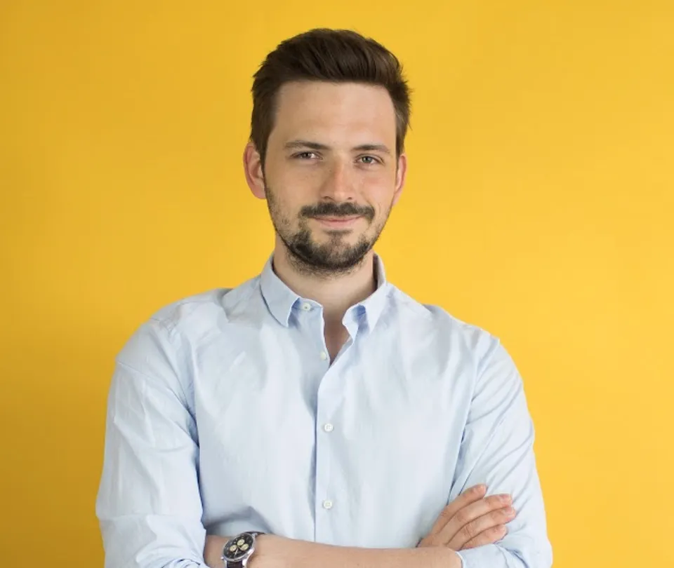 Man in a light blue shirt with arms crossed before a yellow backdrop, leadership portrait at Workpath.