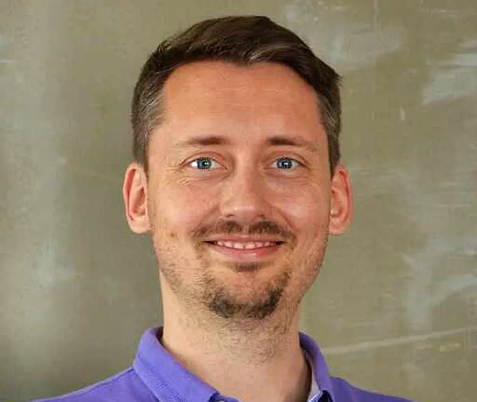 Smiling man in a purple polo, head-and-shoulders portrait against a neutral wall at Workpath.