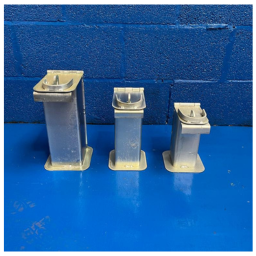 Three metal electrical sockets of varying sizes placed side by side on a blue surface against a blue brick wall.