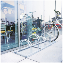 Empty bike rack with a single bicycle locked outside a glass-walled cafe reflecting people inside.