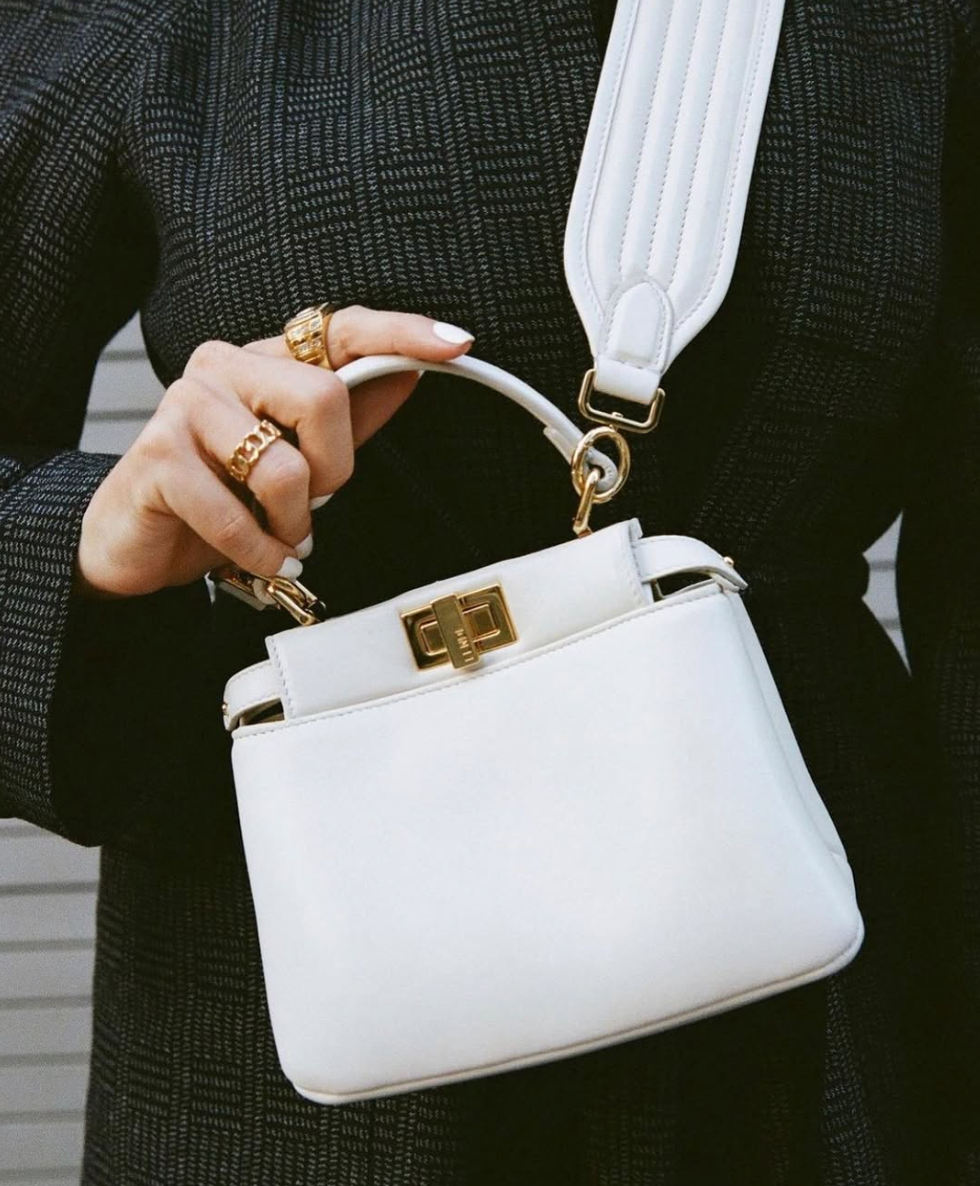 white leather handbag with gold hardware held in hand