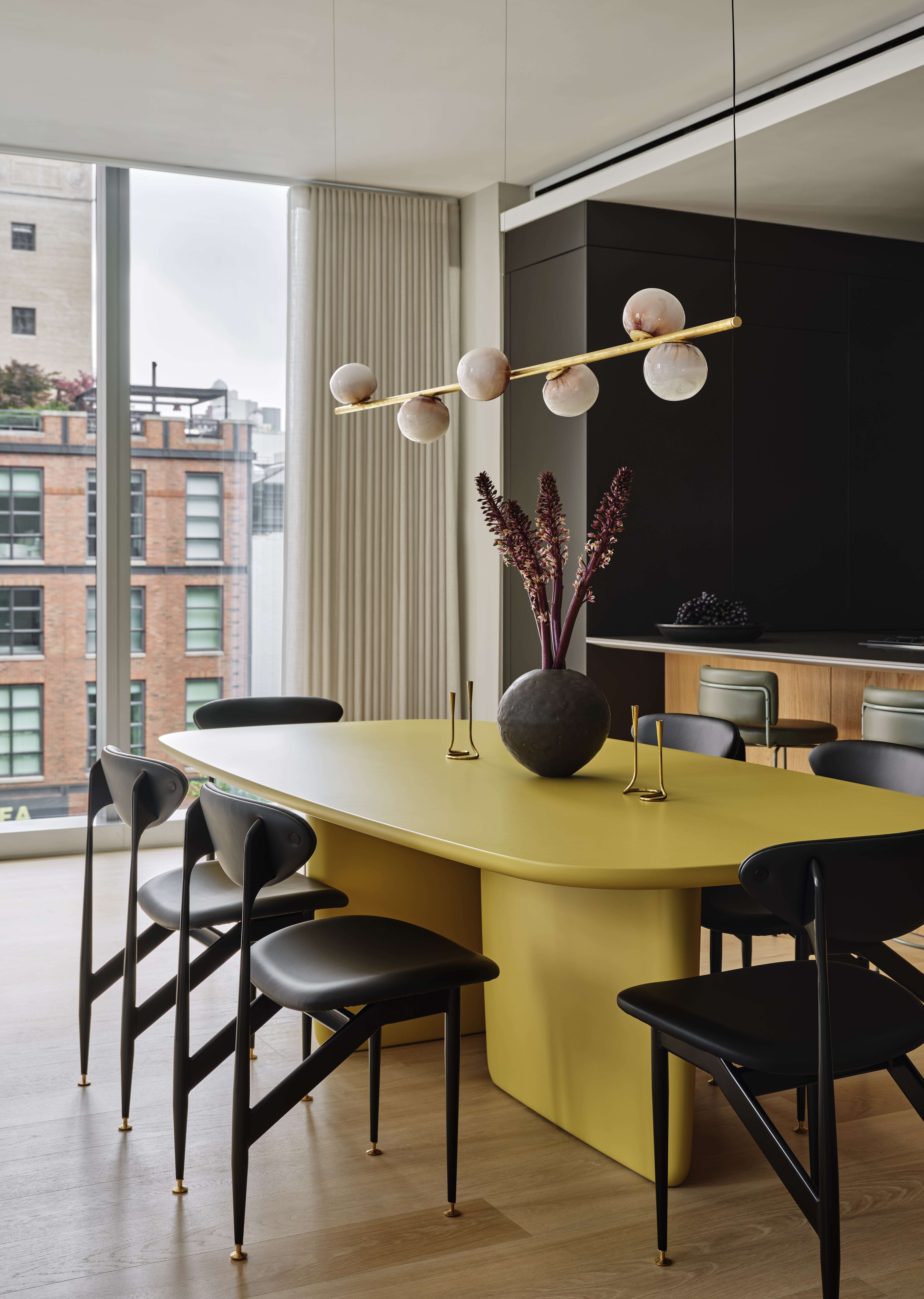 Yellow dining table, black chairs and lighting by Bocci