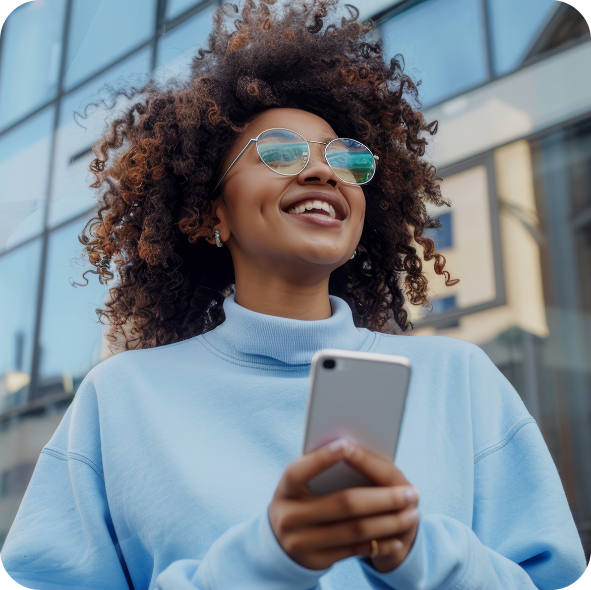 Smiling woman in a light blue jumper holding her phone