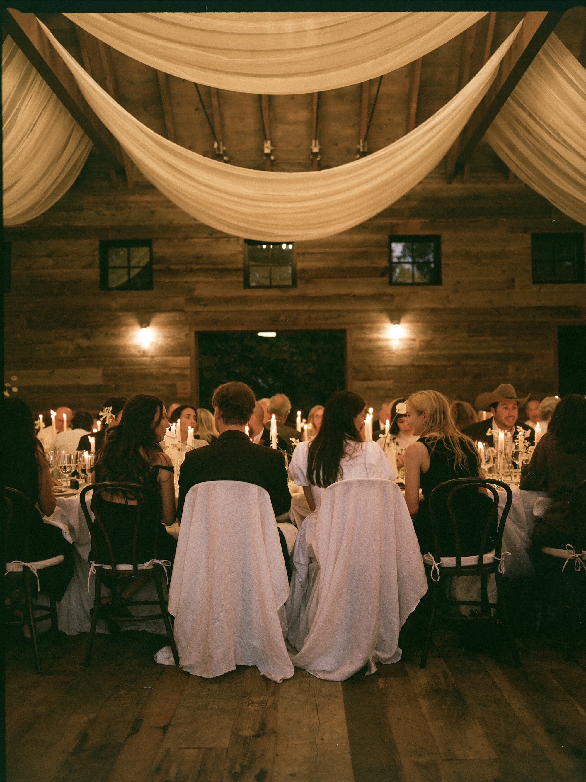 Bride and groom looking out on tent and market lights from the top floor of the Victorian house. 