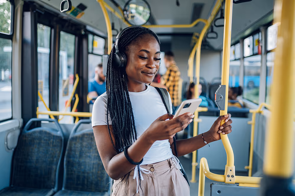 Woman on bus using mobile phone to make online payment