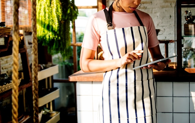 Café owner processing payments on a tablet device at a UK hospitality business