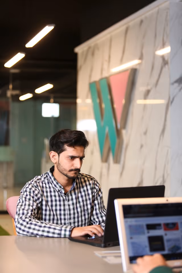 Software developer building a payment platform integration on a laptop in a modern workspace