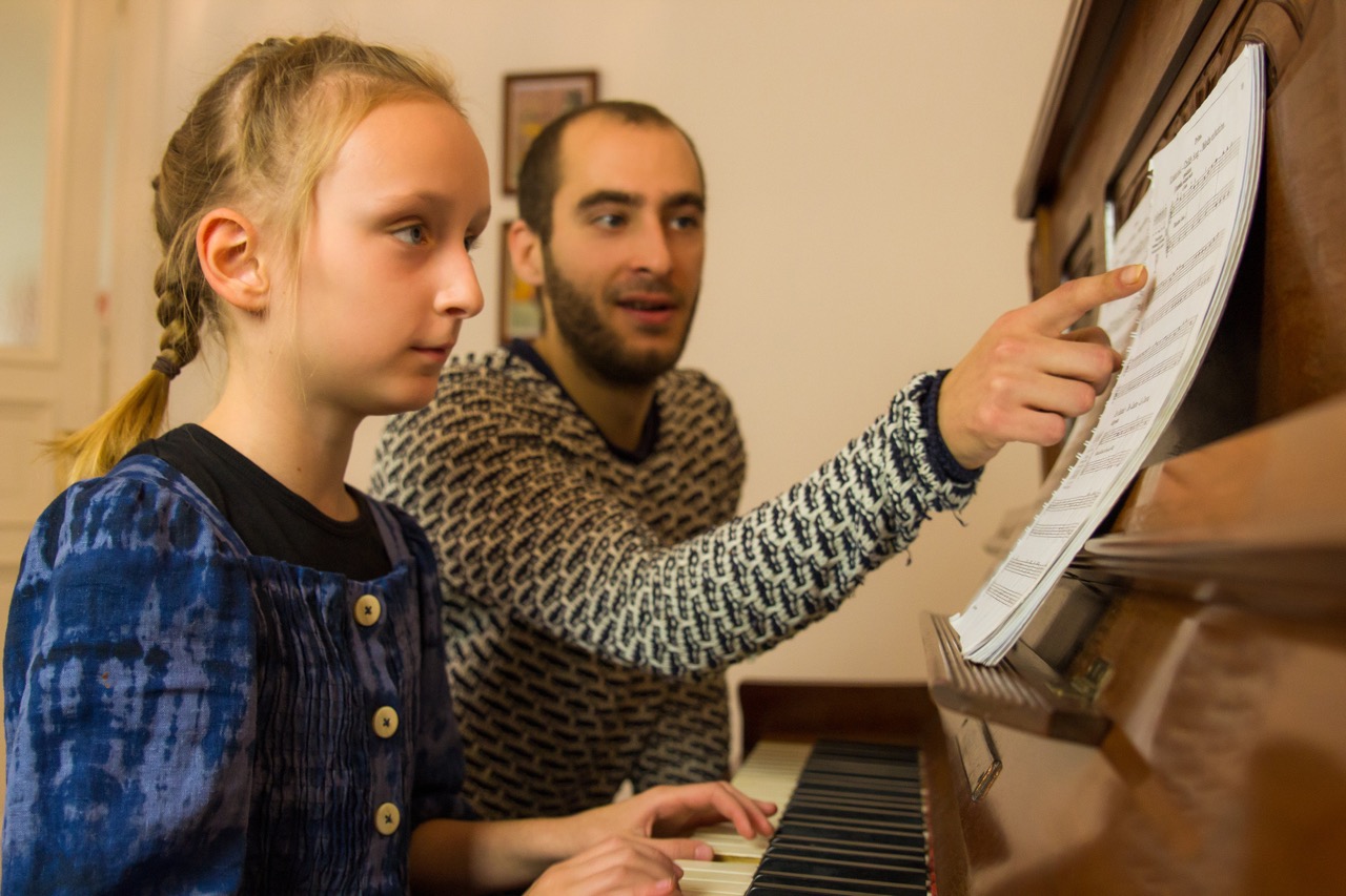 Mädchen beim Klavierunterricht im Wohnzimmer in Berliner Altbauwohnung