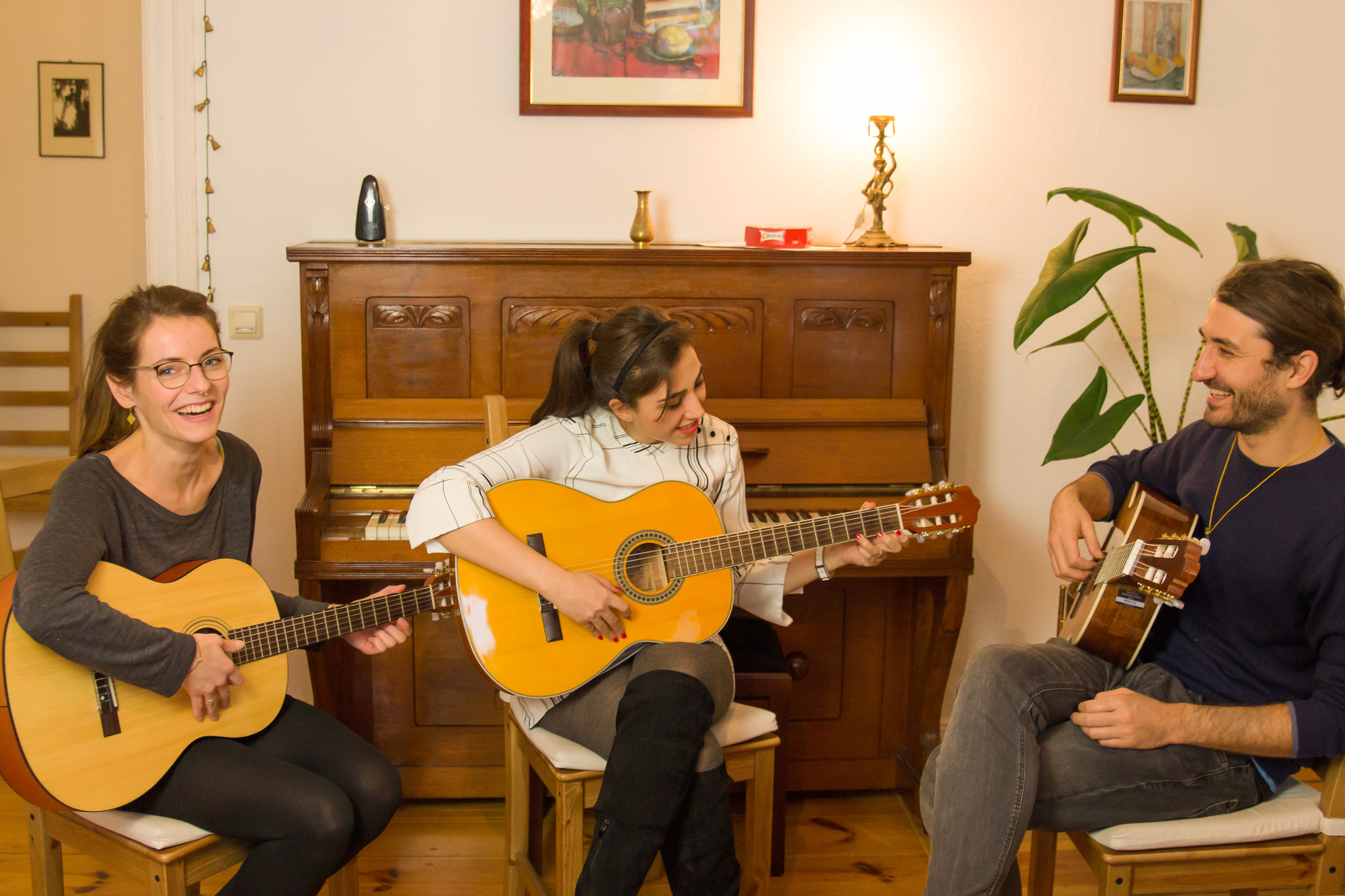 Drei Erwachsene beim freundlichen Gitarrenunterricht in Berlin Pankow