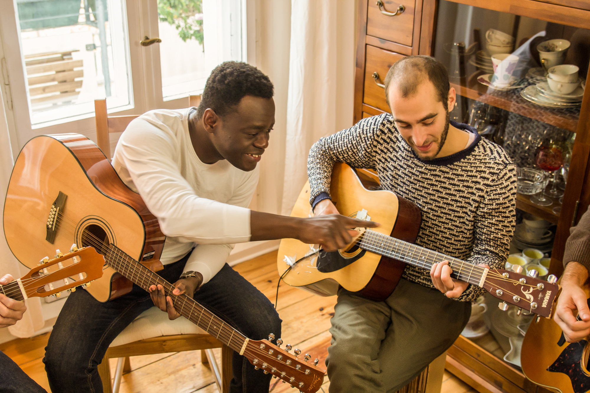 Gitarrenunterricht bei Greifmusic: Lehrkraft zeigt am Griffbrett, mehrere Gitarren sichtbar, Fokus auf gitarrenunterricht berlin lichtenberg