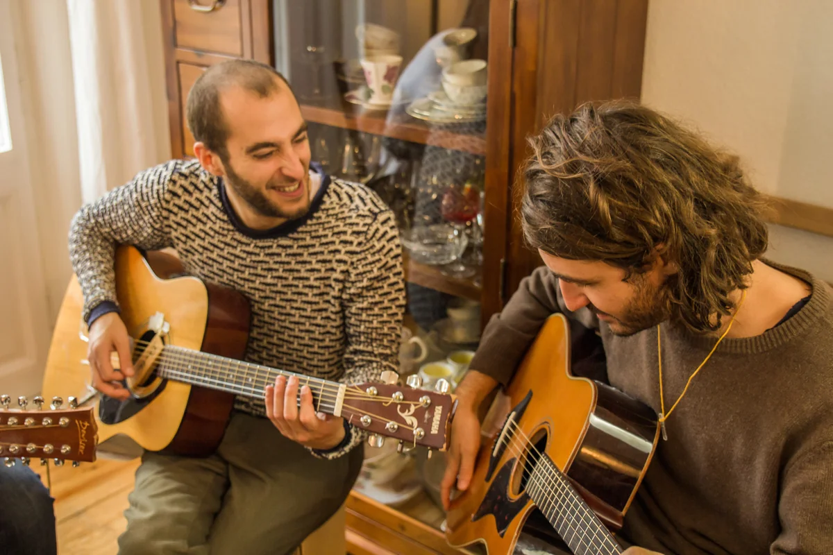 Zwei Erwachsene üben gemeinsam auf akustischen Gitarren.