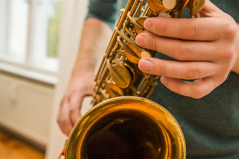 Nahaufnahme einer Hand auf den Klappen eines Saxophons.