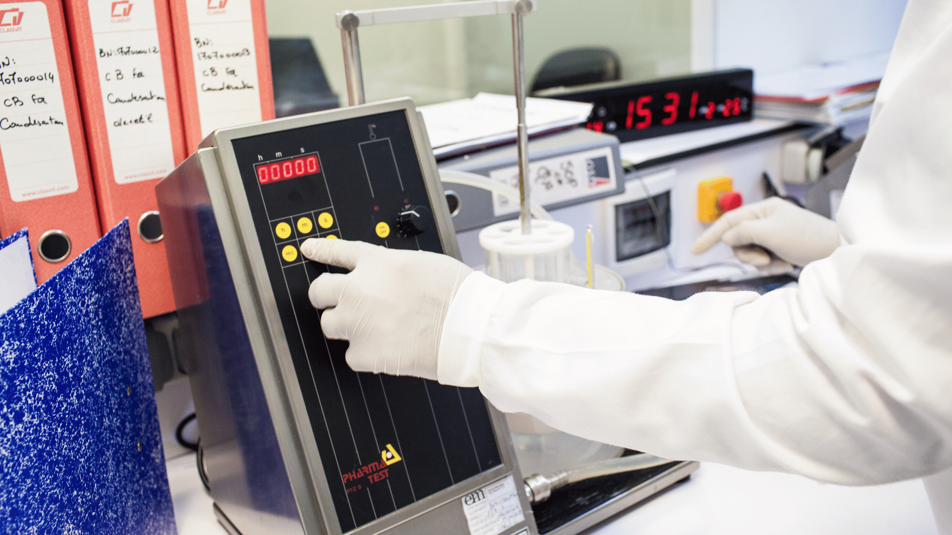 Scientist reviewing connected experimental data on a laboratory computer beside samples and a lab notebook.
