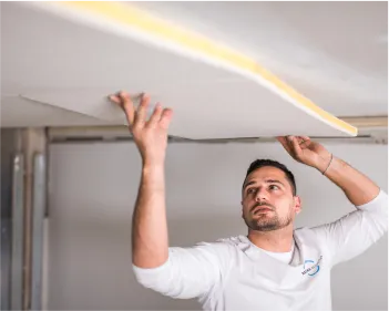 Acoustical plaster panel being installed on a ceiling by BASWA technician