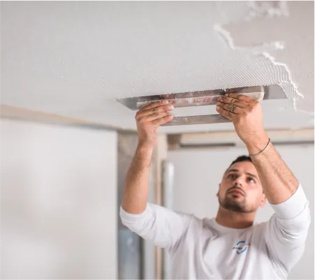 Acoustical plaster being hand-troweled on a ceiling by BASWA technician
